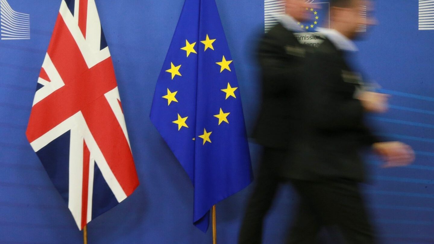 Dos empleados pasan junto a las banderas del Reino Unido y la Unión Europea.