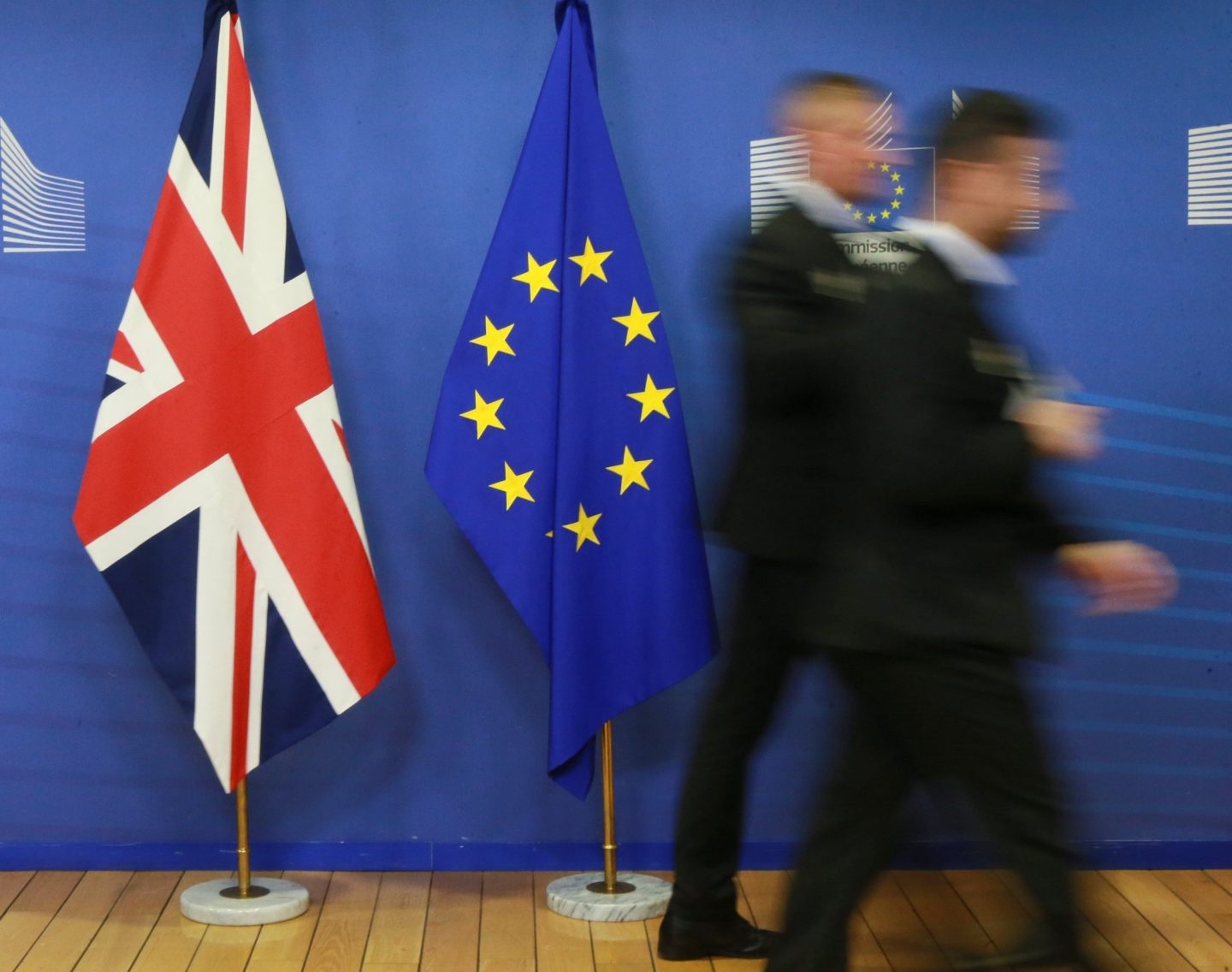 Dos empleados pasan junto a las banderas del Reino Unido y la Unión Europea.
