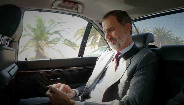 El Rey Felipe consulta el móvil en el coche oficial.