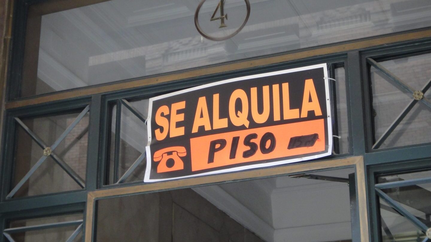 Cartel con el eslogan de 'se alquila' en el portal de un edificio.