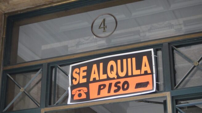 Cartel con el eslogan de 'se alquila' en el portal de un edificio.