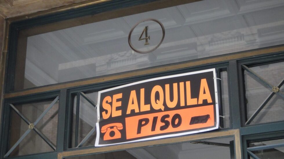 Cartel con el eslogan de 'se alquila' en el portal de un edificio.