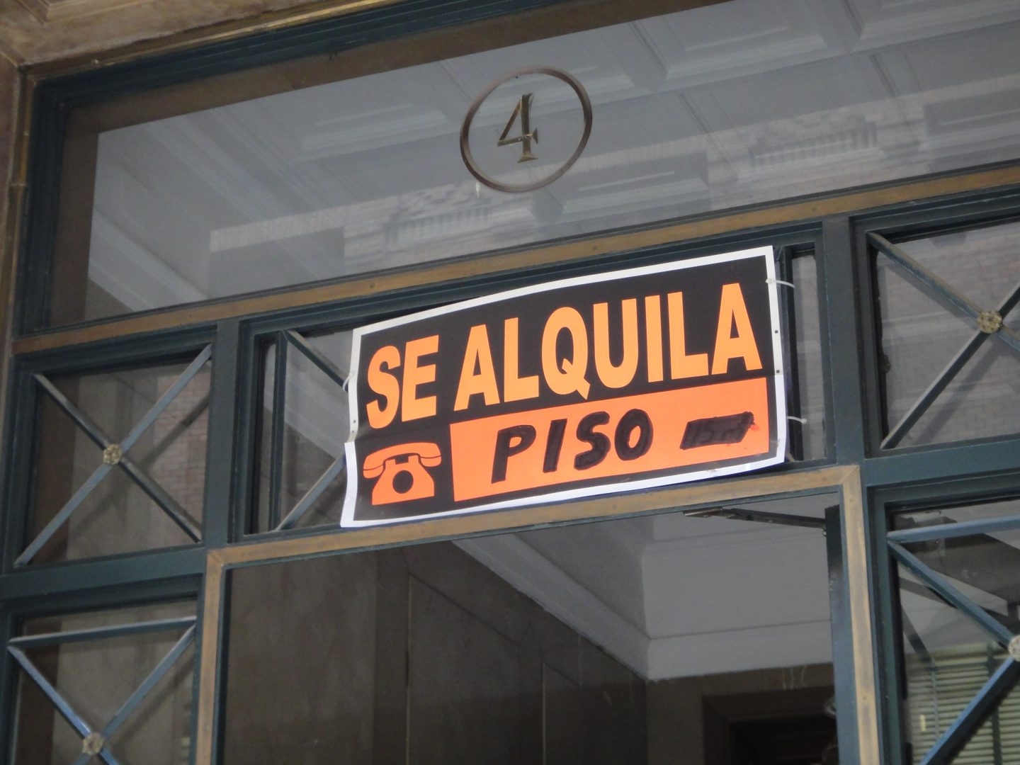 Cartel con el eslogan de 'se alquila' en el portal de un edificio.