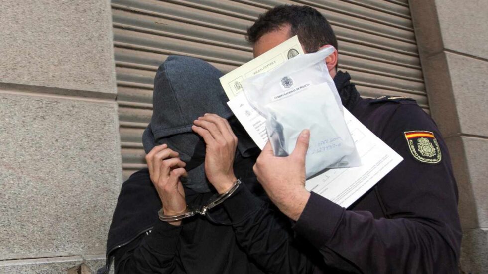 Un policía conduce a un detenido en la jefatura de la policía nacional de Murcia.