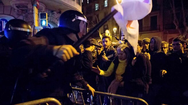 Un agente de los Mossos d'Esquadra recoloca una de las vallas que los manifestantes trataban de echar abajo.