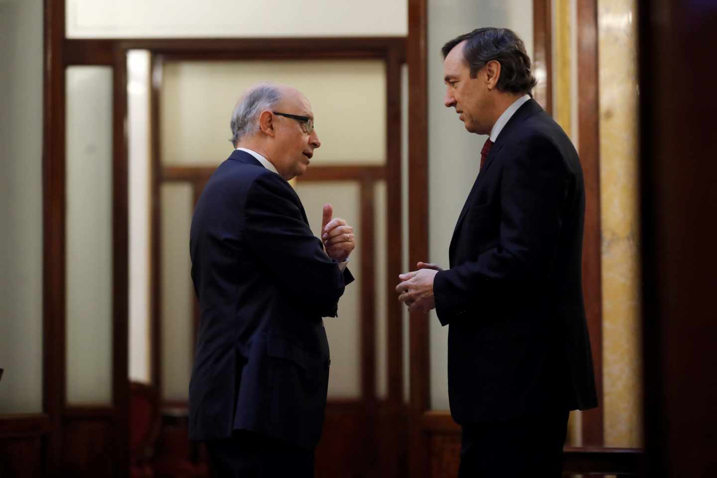 El ministro de Hacienda, Cristobal Montoro, y el portavoz parlamentario del PP, Rafael Hernando, en los pasillos del Congreso.