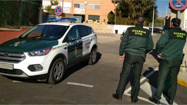 Dos agentes de la Guardia Civil frente a un coche del cuerpo.