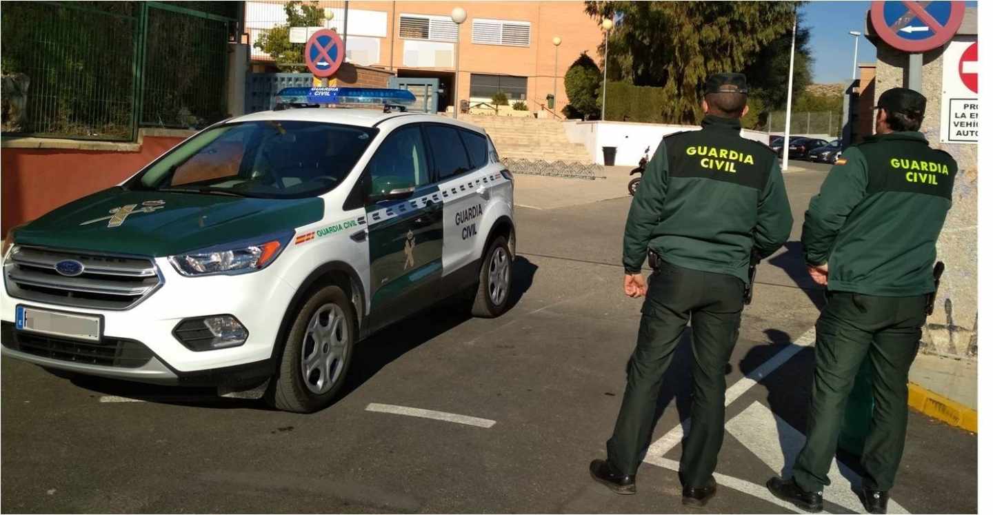 Dos agentes de la Guardia Civil frente a un coche del cuerpo.