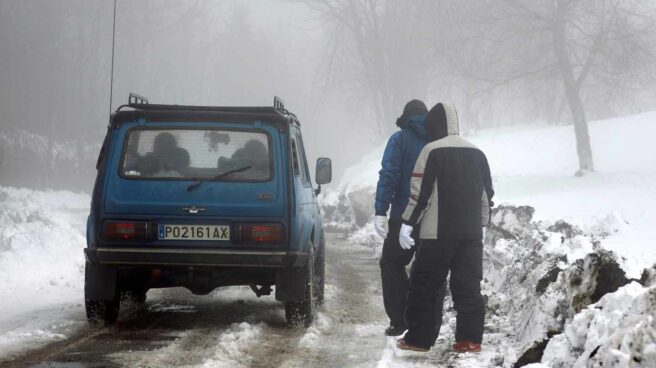 Un coche circula por una carretera nevada en Lugo.