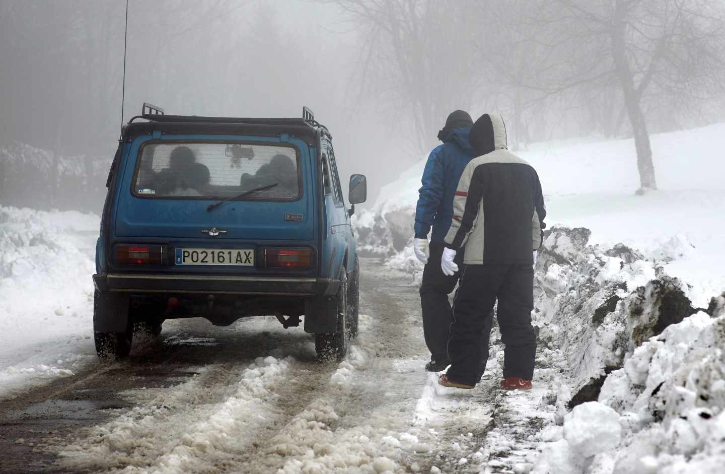 Un coche circula por una carretera nevada en Lugo.