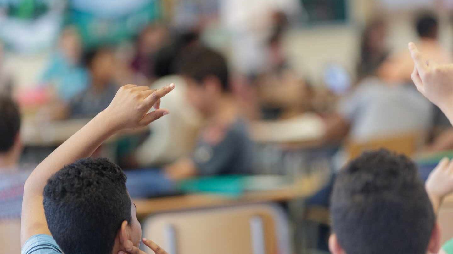 Niños levantan la mano en un aula.