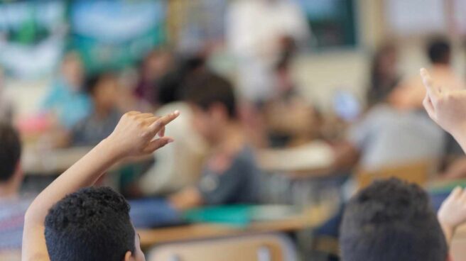Niños levantan la mano en un aula.