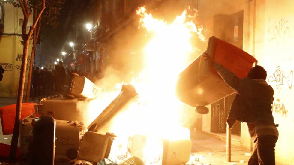 Un joven lanza contenedores al fuego en la noche del pasado jueves en el barrio de Lavapiés.