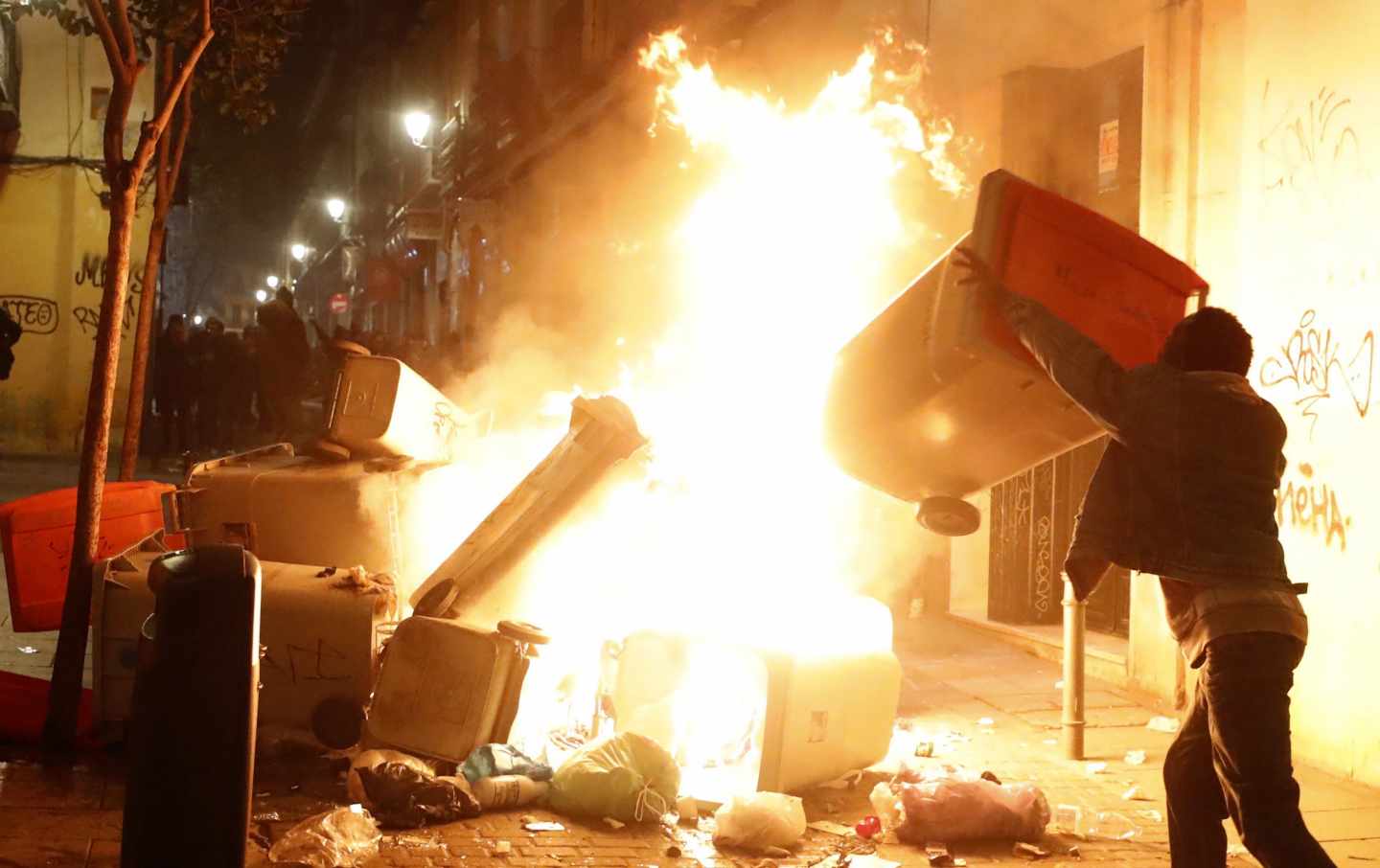 Un joven lanza contenedores al fuego en la noche del pasado jueves en el barrio de Lavapiés.