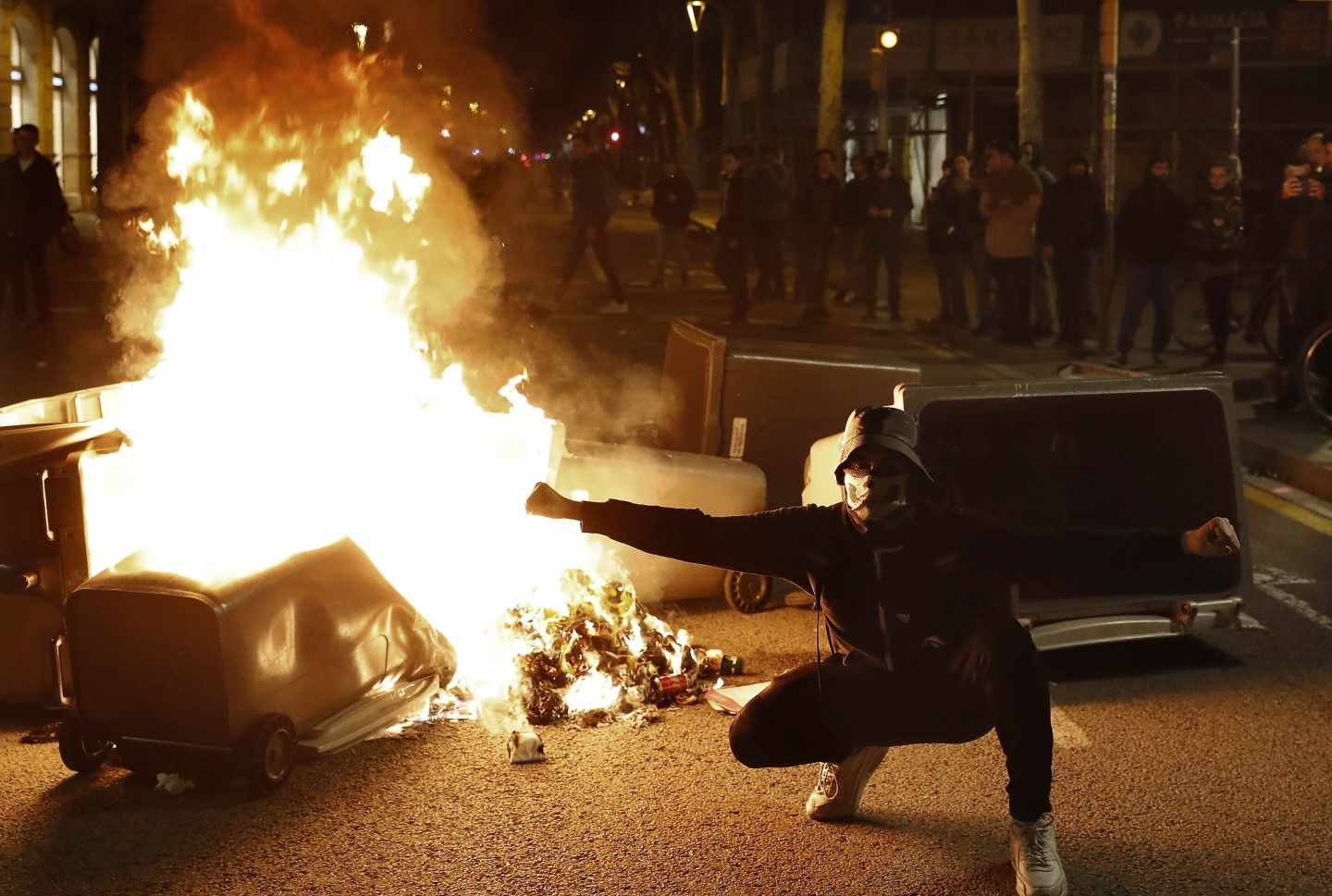 Un manifestante, junto a uno de los contenedores incendiados en Barcelona durante los disturbios del 25 de marzo.