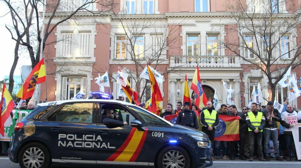 Un patrullero de la Policía Nacional pasa junto a una concentración en vísperas de que se firmase el acuerdo de equiparación salarial.