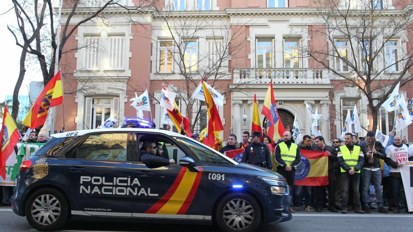 Un patrullero de la Policía Nacional pasa junto a una concentración en vísperas de que se firmase el acuerdo de equiparación salarial.