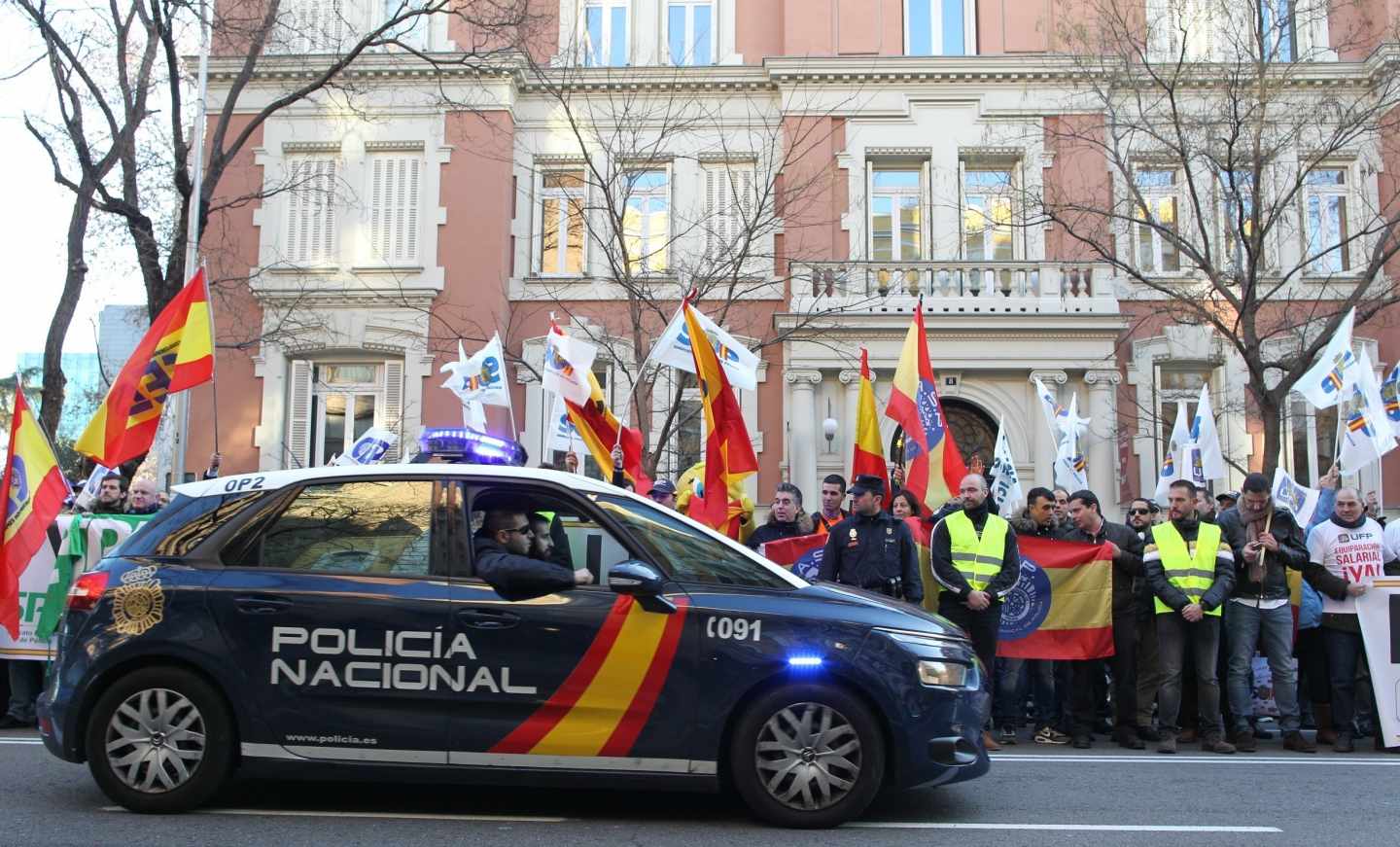 Un patrullero de la Policía Nacional pasa junto a una concentración en vísperas de que se firmase el acuerdo de equiparación salarial.