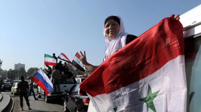 Una mujer siria sujeta una bandera en Damasco.