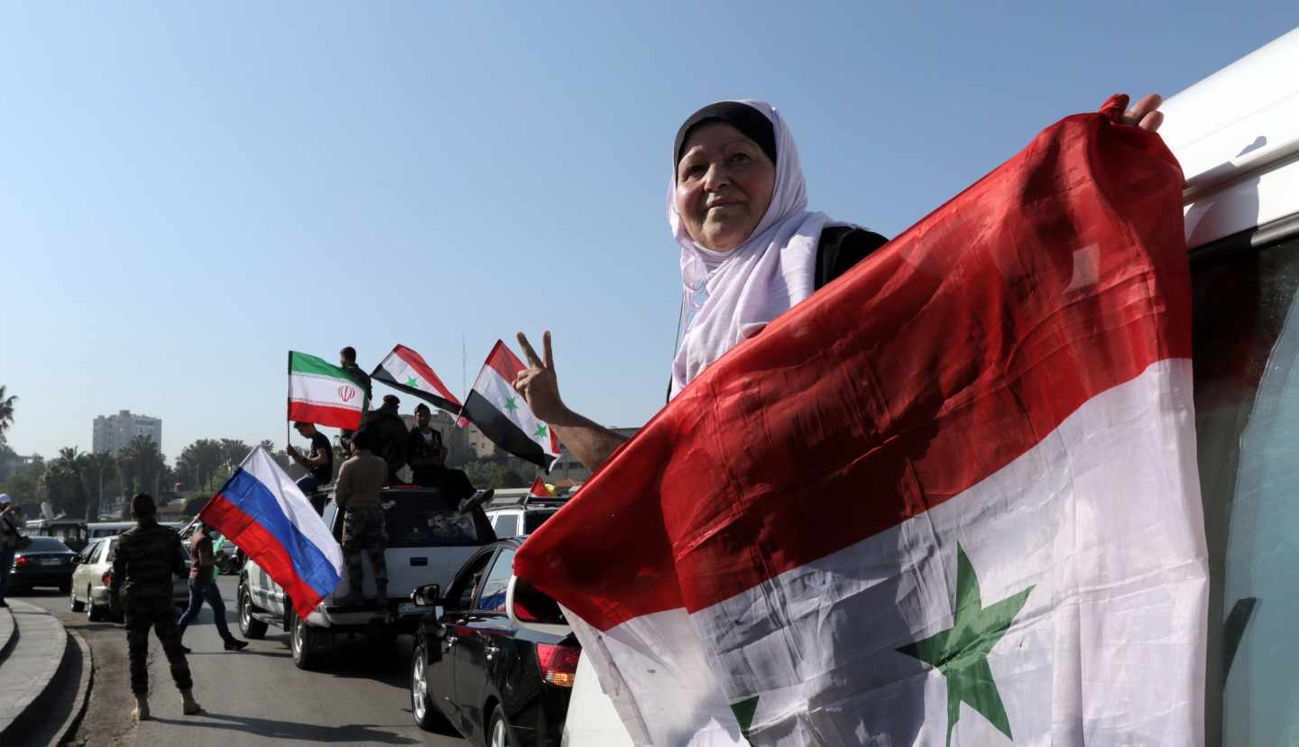 Una mujer siria sujeta una bandera en Damasco.