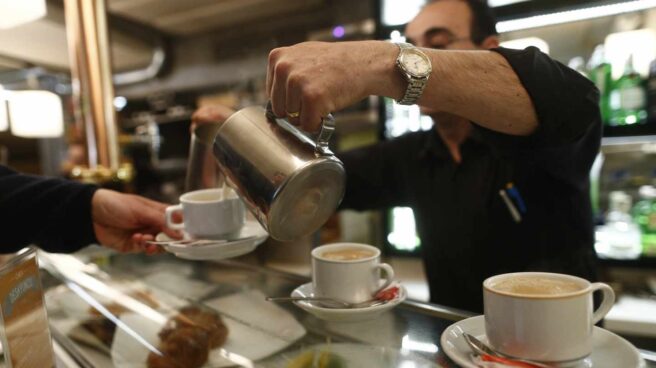 Un camarero sirve unos cafés dentro de un bar