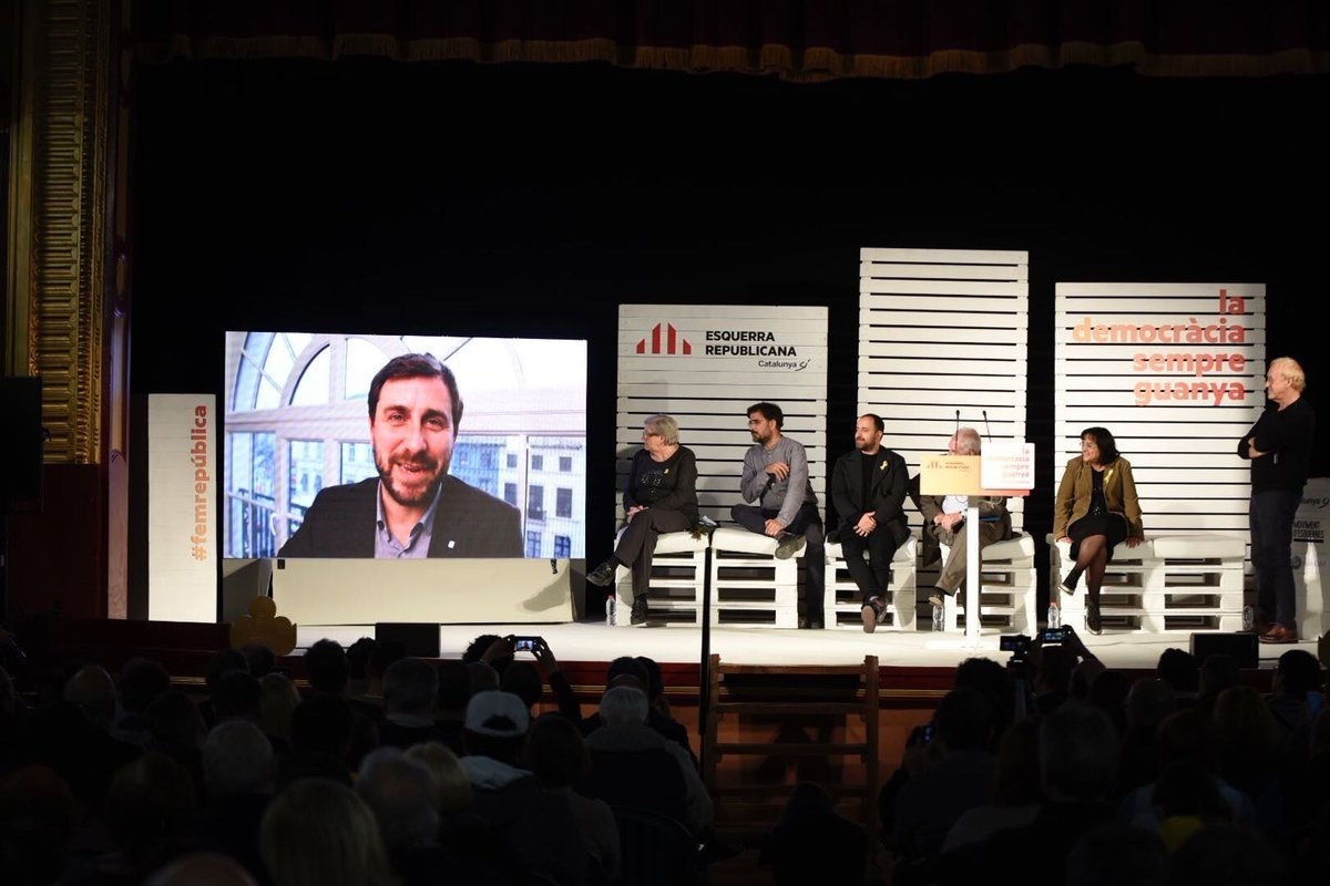 El diputado de ERC Toni Comín interviene en vídeo durante un mitin en campaña electoral.