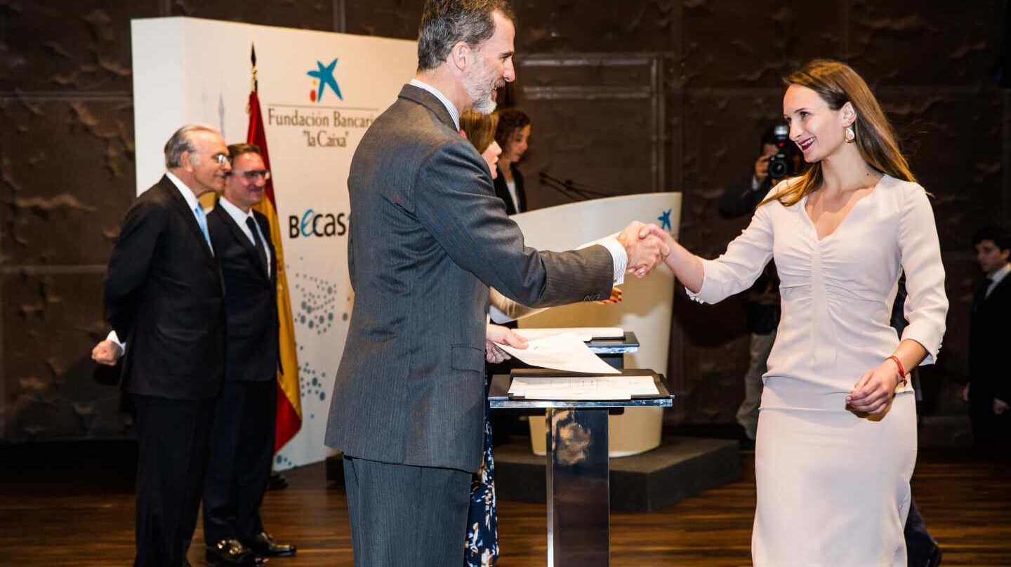 El rey Felipe VI saluda a una de las estudiantes becadas por la Fundación La Caixa.