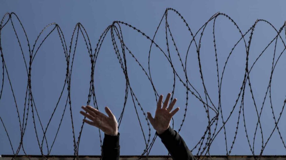 Un mena (menor migrante no acompañado) frente a la vaya de Ceuta.