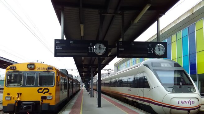 Un tren de CP (Portugal) y otro de Renfe parados en una estación, en andenes contiguos.