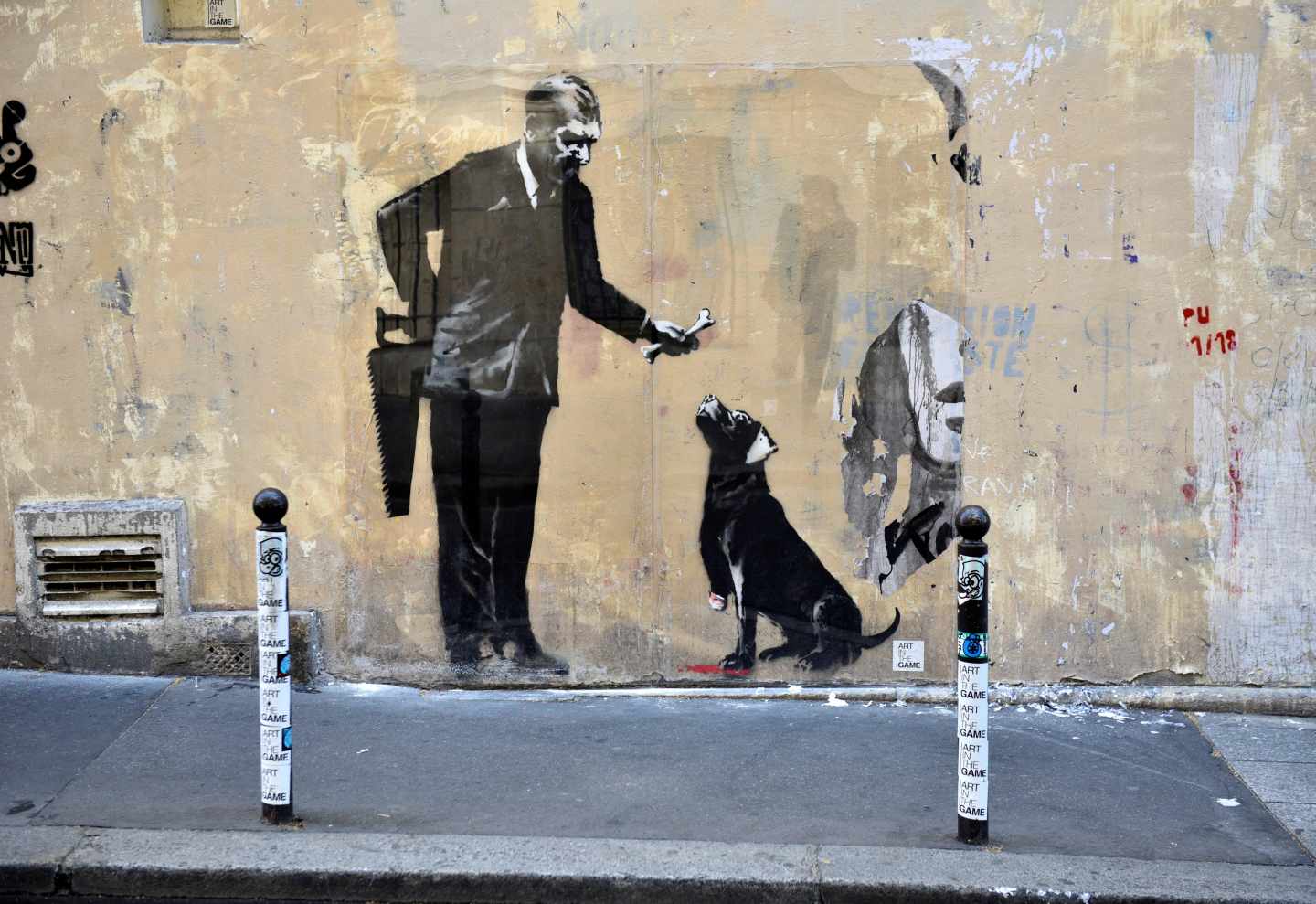 Pintura de Banksy en la que se ve a un hombre dando de comer a un perro, pintura localizada cerca de la Sorbona