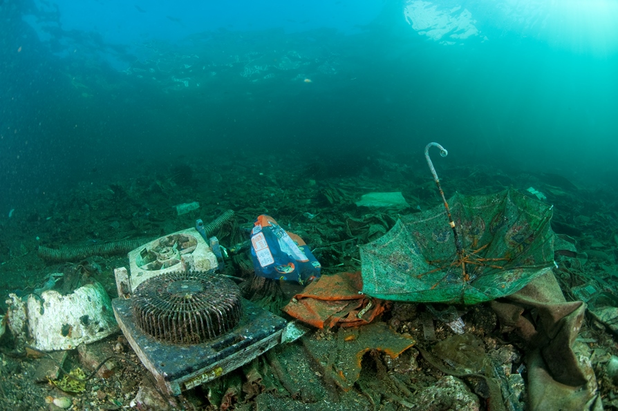 Basura en el fondo del mar.: un ventilador, un paraguas y ropa