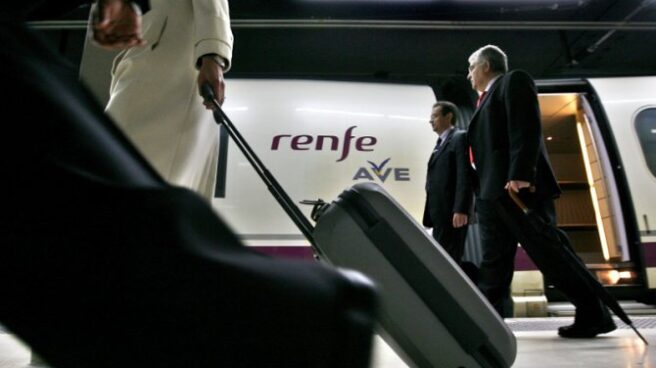 maquinistas Renfe AVE Pasajeros caminan por el andén donde está estacionado un tren AVE.
