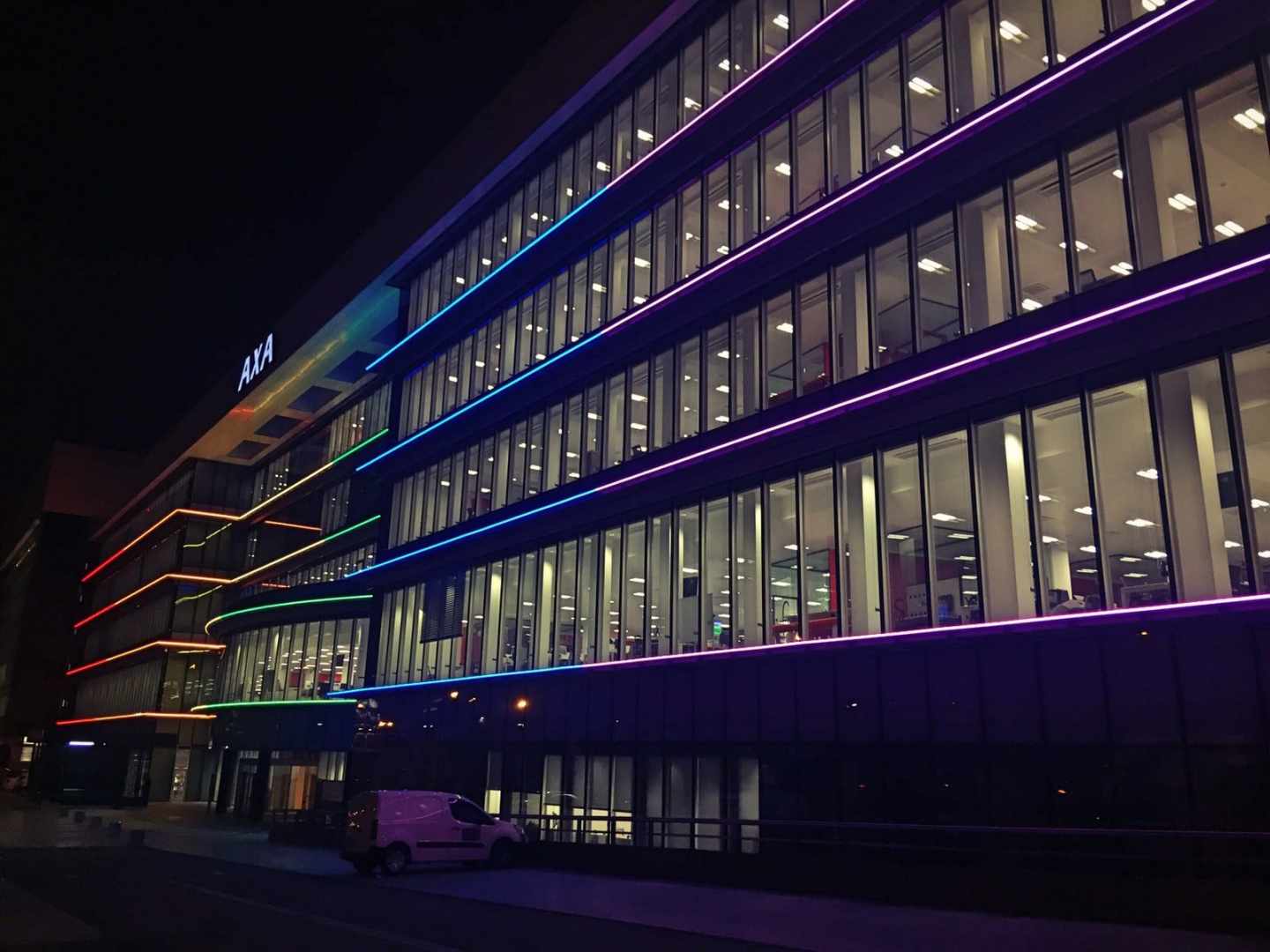 Sede de Axa iluminada con la bandera del arco iris.