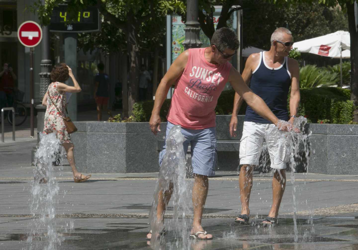 Hombre sofocando el calor en una fuente pública