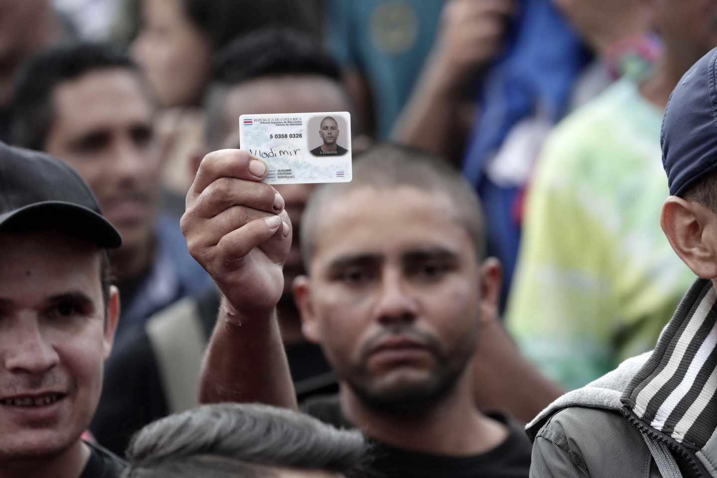 Un hombre muestra su cédula de identidad como protesta junto a cientos de costarricenses