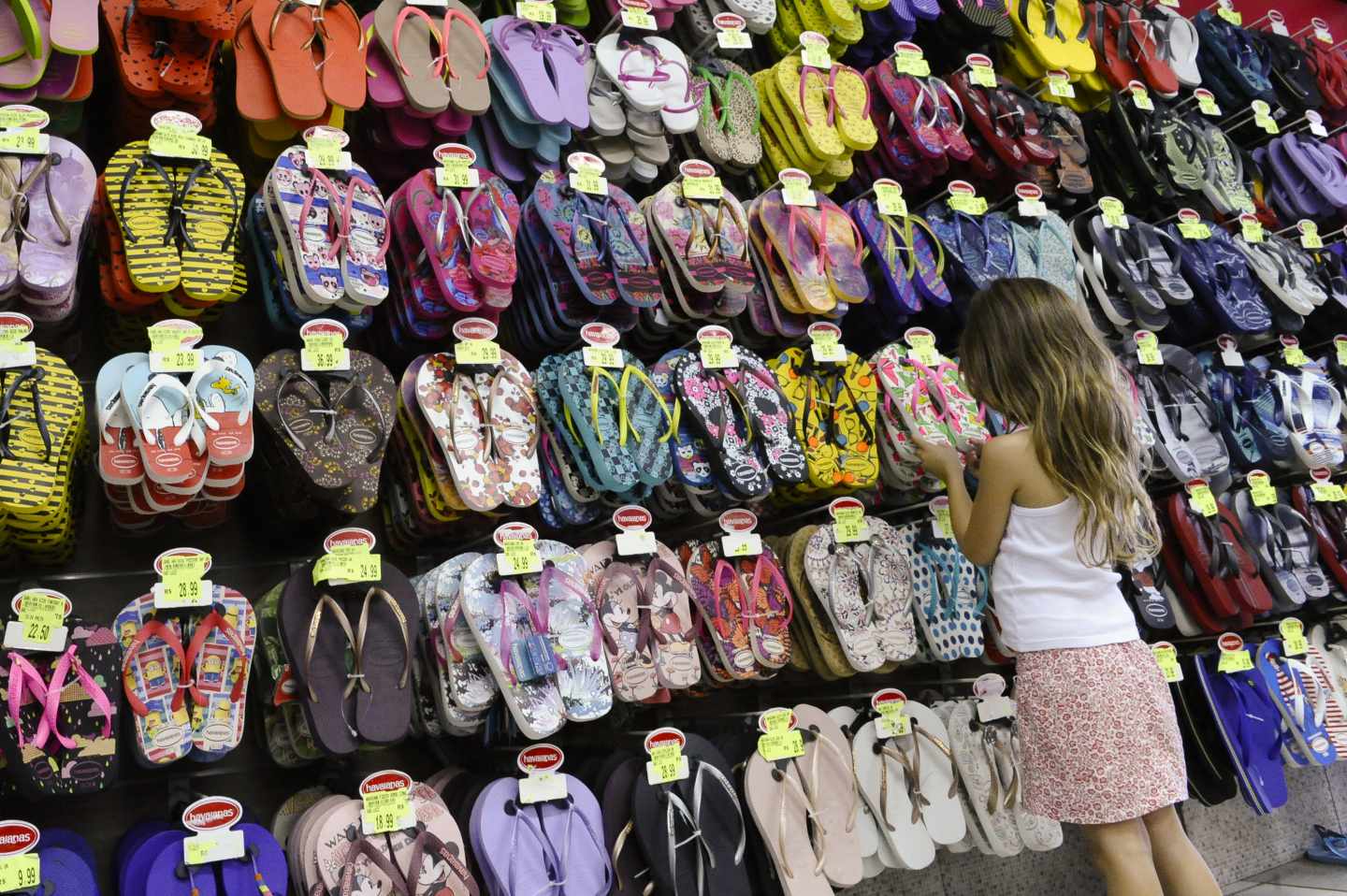 Una niña mirando sandalias en una tienda