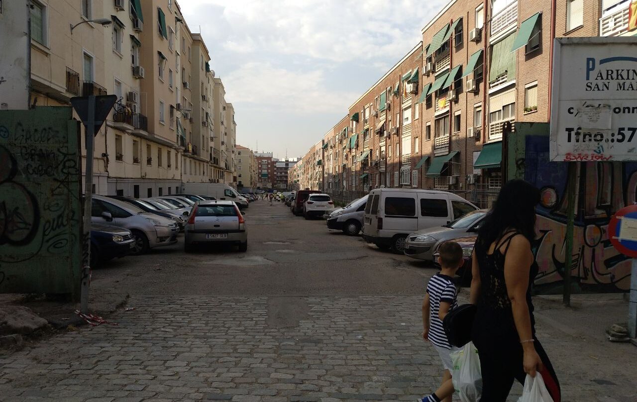 Una mujer y su hijo pasan junto a la calle fantasma del Barrio de La Elipa, hoy convertida en aparcamiento.