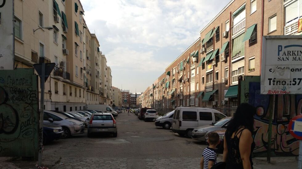 Una mujer y su hijo pasan junto a la calle fantasma del Barrio de La Elipa, hoy convertida en aparcamiento.
