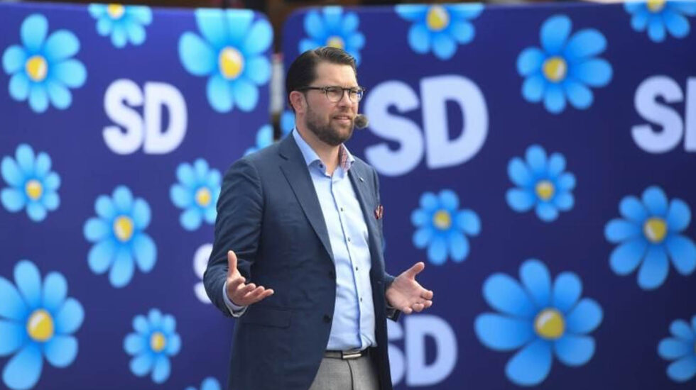 Jimmie Akesson, líder de los Demócratas de Suecia, en un mitin con la flor con los colores de la bandea sueca de fondo.