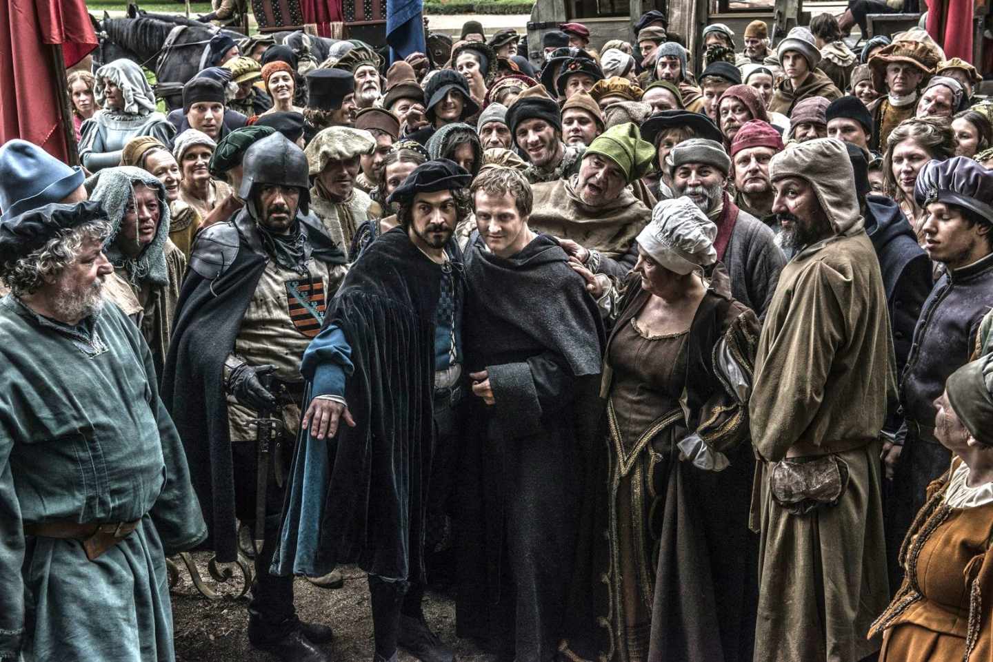 Fotograma de la serie "Lutero: la reforma" en la que se ve al protagonista rodeado de mucha gente