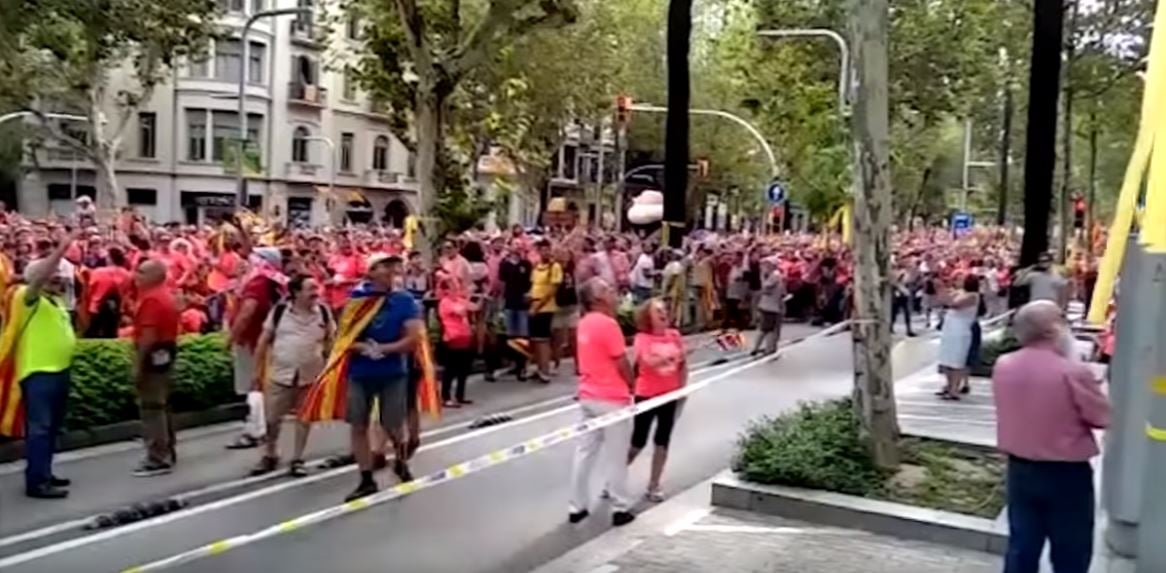 Manifestantes de la Diada miran hacia el balcón desde el que suena el himno.