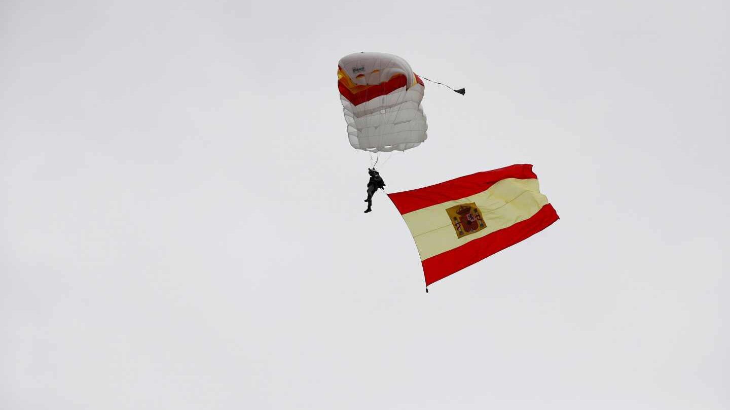 Un paracaidista desciende al inicio del desfile de la Fiesta Nacional.