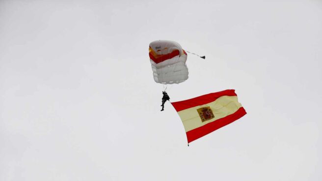 Un paracaidista desciende al inicio del desfile de la Fiesta Nacional.