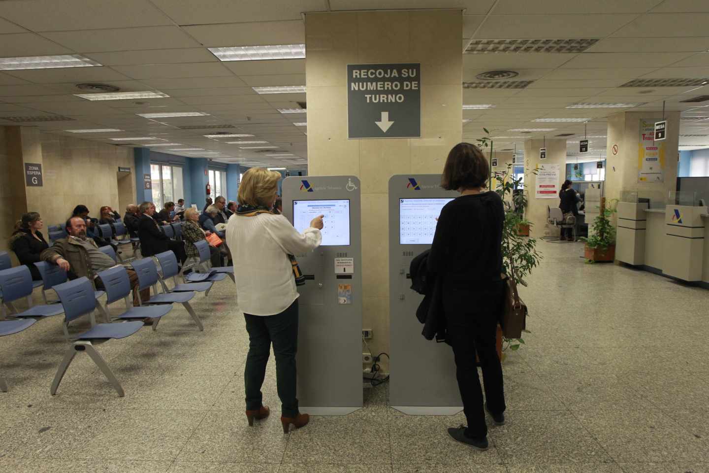 Dos mujeres piden turno en una oficina de la Agencia Tributaria.