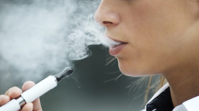 Una mujer fumando un cigarrillo electrónico Una mujer fumando un cigarrillo electrónico