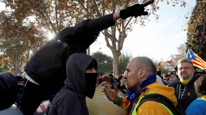 Un manifestante independentista trata de impedir que un grupo de encapuchados vuelquen contenedores