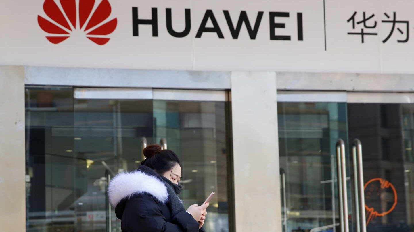 Una china pasa junto a una tienda de móviles Huawei en Pekín.