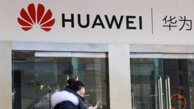 Una china pasa junto a una tienda de móviles Huawei en Pekín.