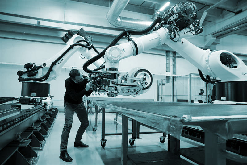 Un trabajador utiliza robots educados con Inteligencia Artificial en una cadena de montaje.