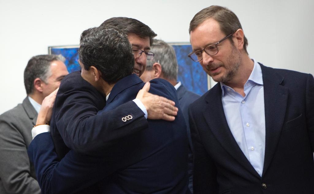 Juan Marín y Juanma Moreno se abrazan ante Javier Maroto en el parlamento andaluz.